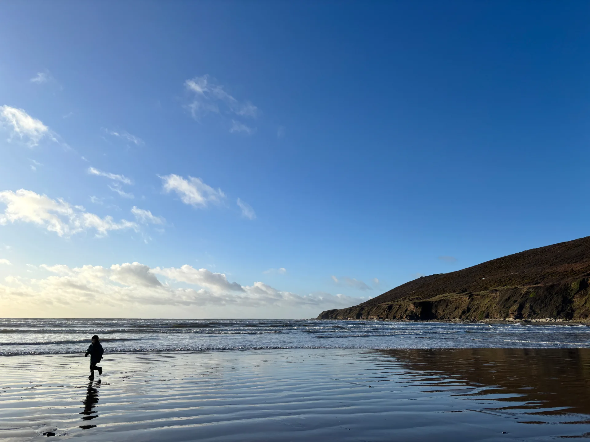 Saunton beach with blue sky, sea and a person on the sand